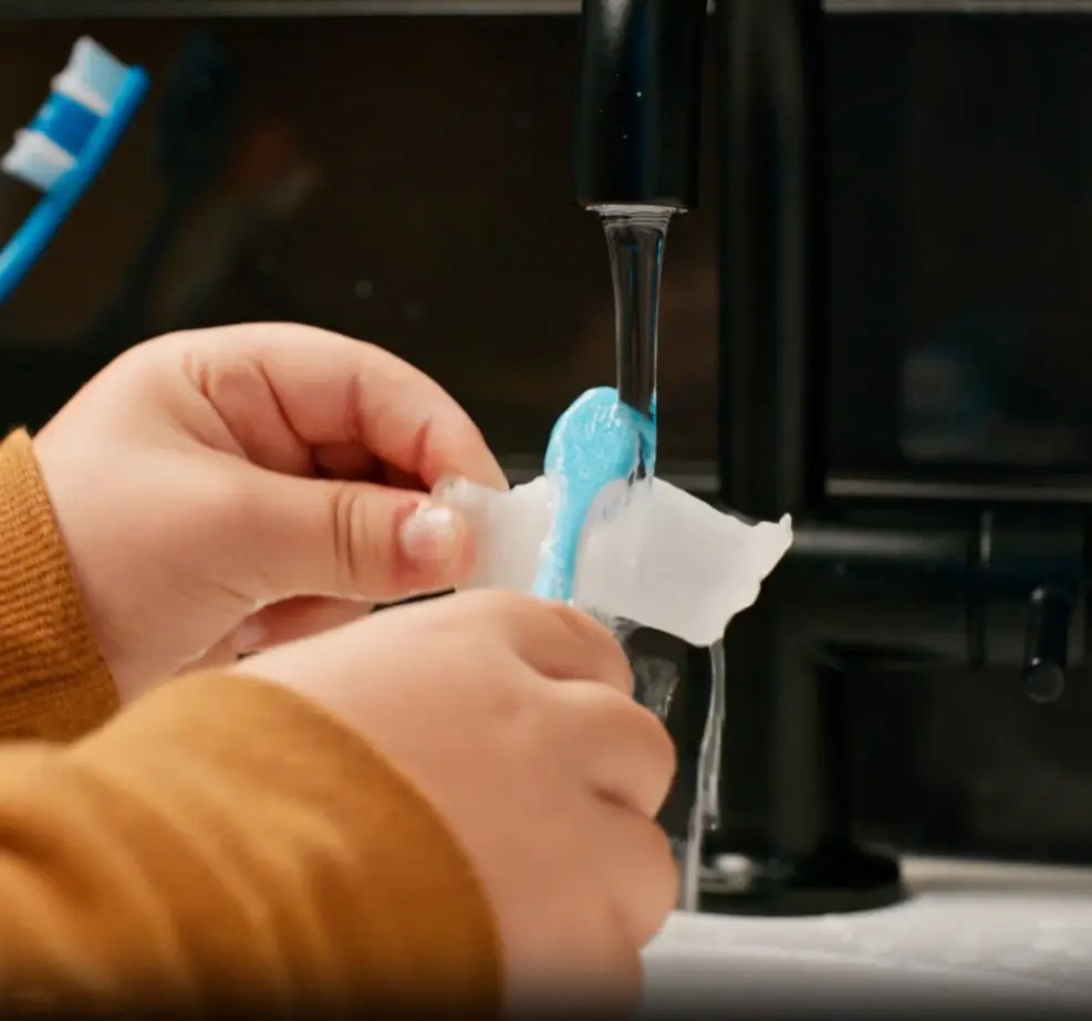 Brushing clean an Invisalign aligner in the sink.