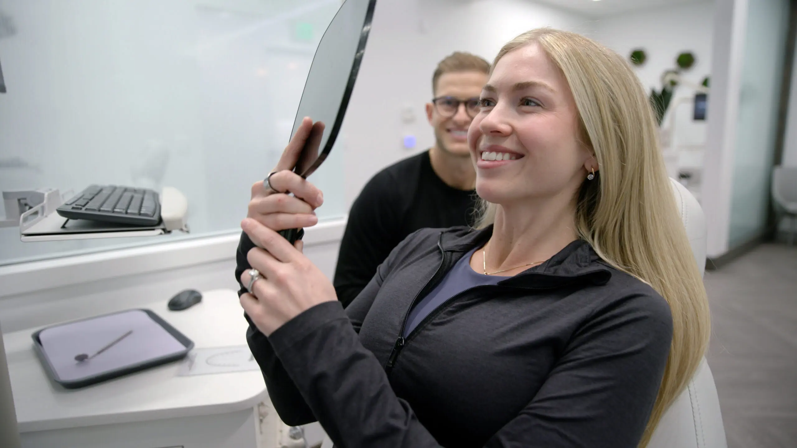Smiling woman holding a mirror.