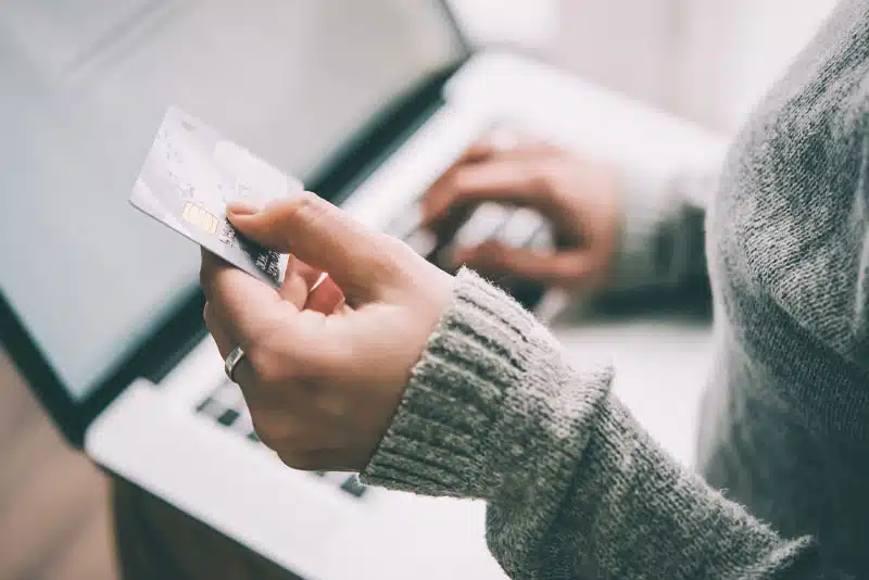 Person holding credit card, using laptop.